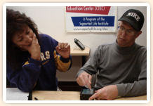 Woman watches man using a stylus with small device