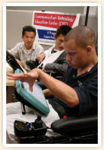 Two men watch another using his communication device